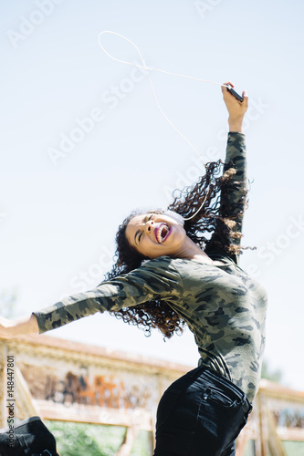 Latin girl jumping happily with earphones