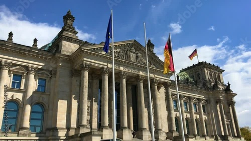 Eingang Deutscher Bundestag Berlin mit wehenden Deutschland-Flaggen bei schönem Wetter mit blauen Himmel und Sonnenschein