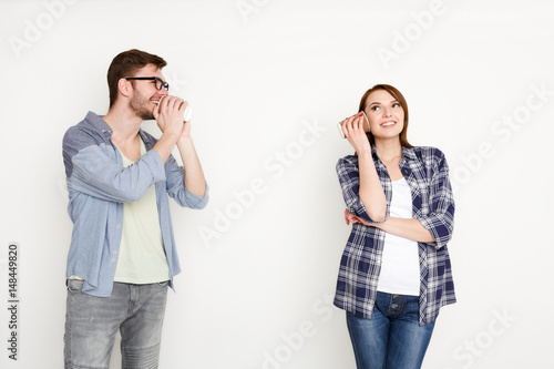 Young casual couple talking through tin can phone