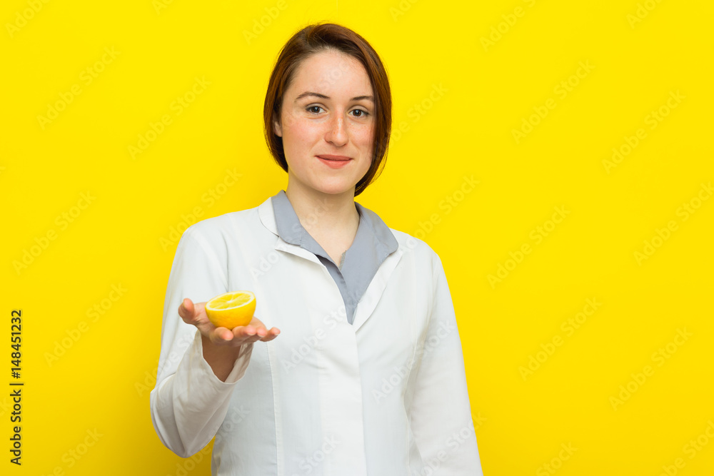 Young female nutritionist with half citrus on yellow background Young female nutritionist with half citrus on yellow background
