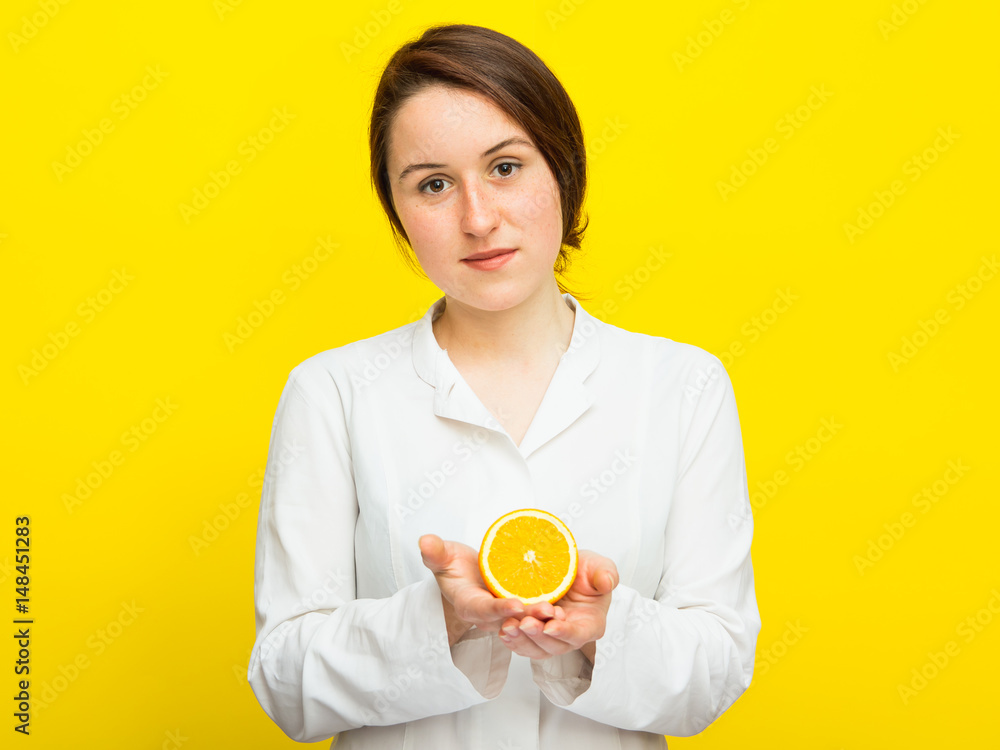 Young female nutritionist with half citrus on yellow background Young female nutritionist with half citrus on yellow background
