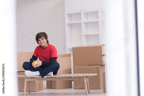 boy sitting on the table with cardboard boxes around him