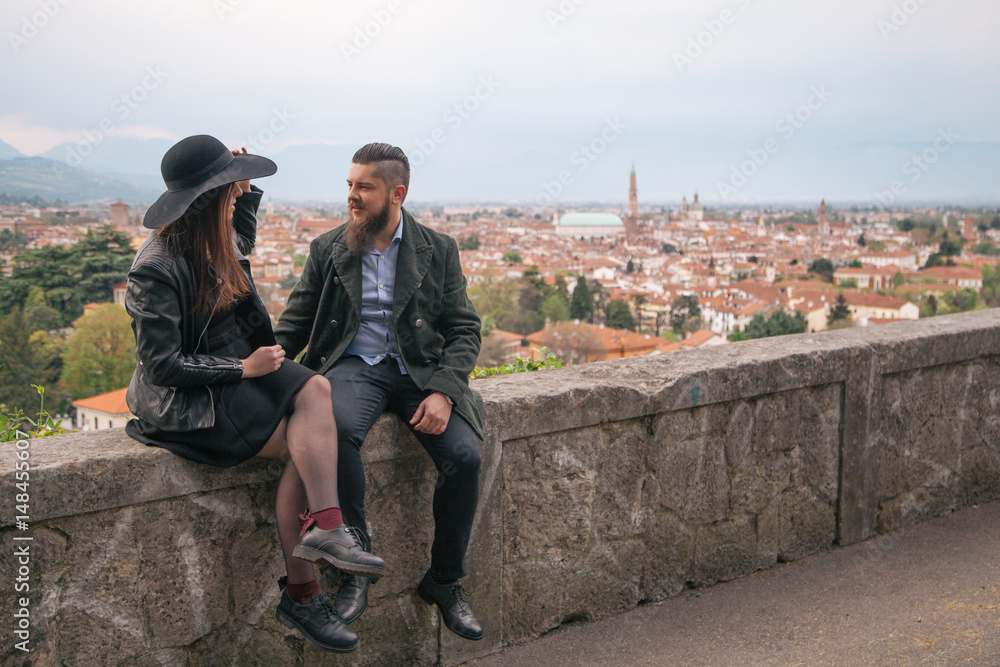 Fototapeta premium Young modern hipster couple in love. Deep moment of a love story with a vintage look, city view in the background. 