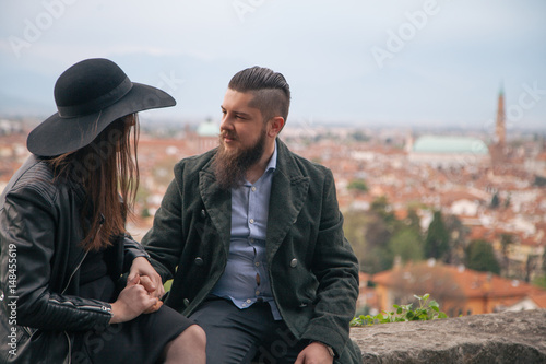 Young modern hipster couple in love. Deep moment of a love story with a vintage look, city view in the background.  © Andphotography