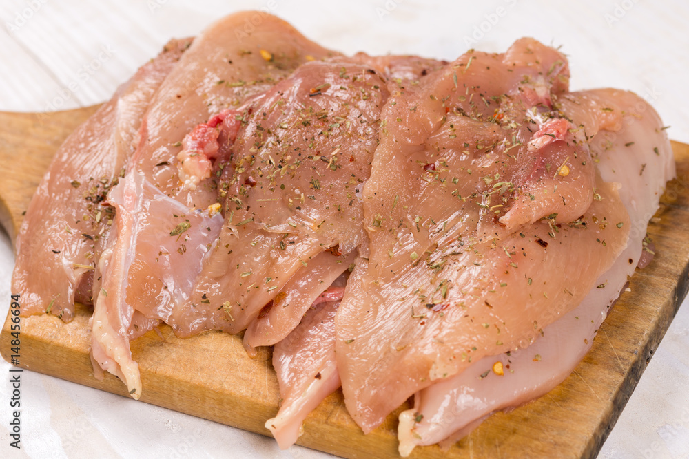 Raw chicken breasts on the wooden board spiced for barbecue Raw chicken breasts on the wooden board spiced for barbecue