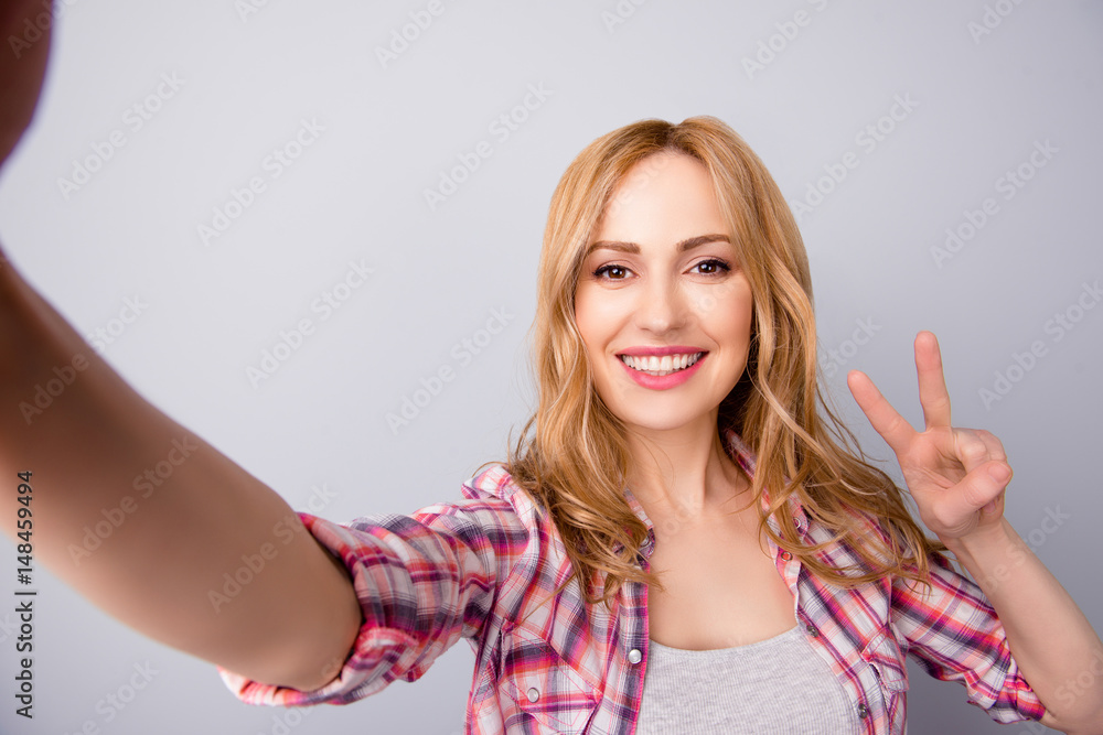 Young beautiful woman in checkered shirt taking self portrait and showing v-sign Young beautiful woman in checkered shirt taking self portrait and showing v-sign