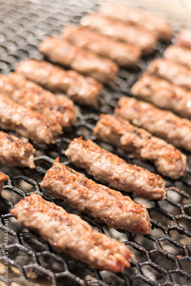 Grilling minced meat kebabs on the barbecue with selective focus