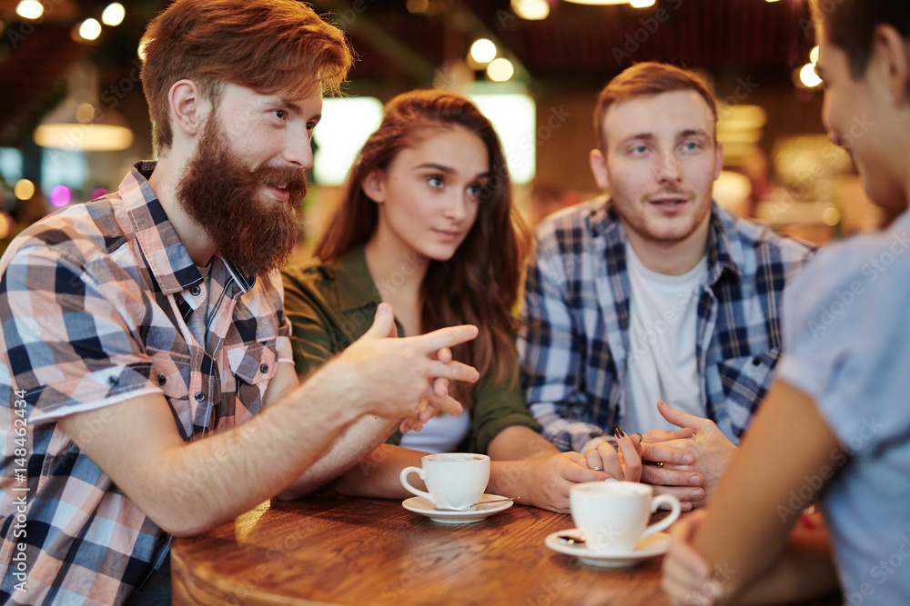 Group of creative interior designers discussing promising joint project while having coffee break in lovely small cafe, waist-up portrait