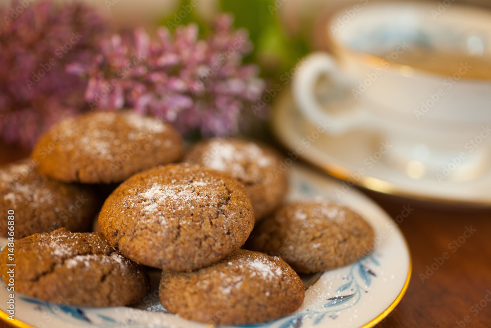 a plate of Molasses cookies with green tea in a vintage porcelain teacup with purple flowers 