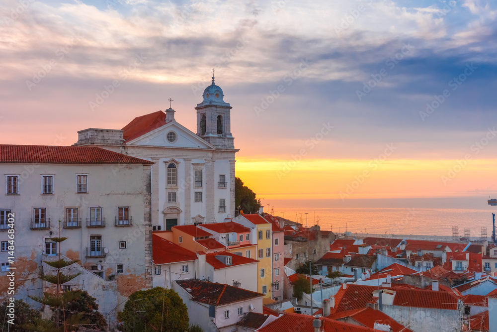 Fototapeta premium View of Alfama, the oldest district of the Old Town, with Church of Saint Stephen at cloudy sunrise, Lisbon, Portugal