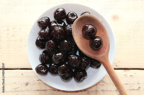 Amarena cherries on a White plate with a wooden spoon