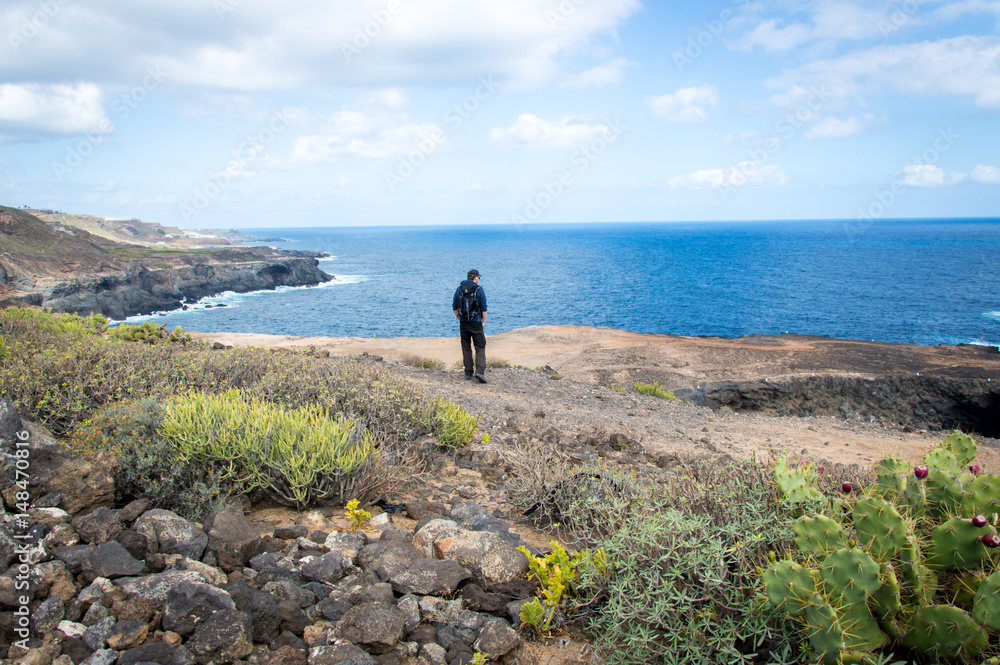 One person standing in beautiful landscape with cliffs and sea in Gran Canaria, Canary Islands - Stock Photo