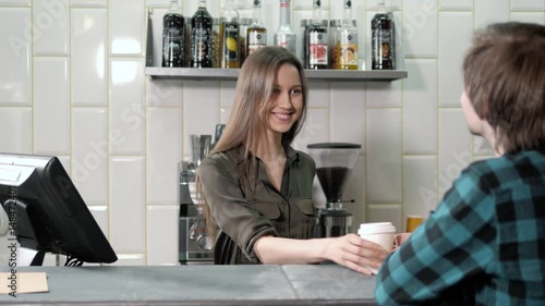 Man using mobile payment in a coffee shop, man take coffee and pay contactless with NFC chip, smiling woman near cahbox photo