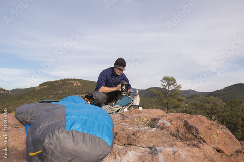 man boiling water at camp on top of a mountain