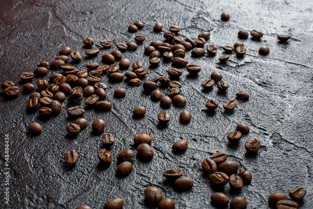 Grains of coffee are scattered on a black stone Grains of coffee are scattered on a black stone