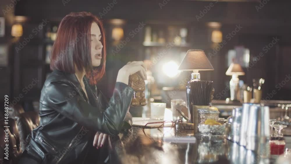 20s sexy beauty redhead woman in black leather jacket is drink cocktail, looking at camera and flirt smiles in the bar 20s sexy beauty redhead woman in black leather jacket is drink cocktail, looking at camera and flirt smiles in the bar