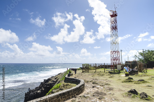 Coastline view with beautiful sky and clouds from promontory with meteorological lookout tower and people having a picnic at windy Gris-Gris in Mauritius island, Indian Ocean.