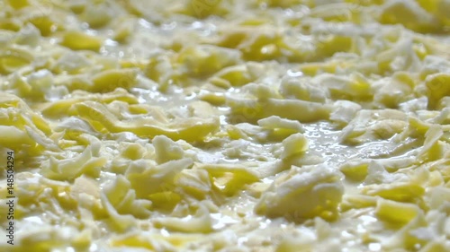 Cooking pizza. Grated cheese on the raw pizza. Close-up. Slow motion. photo