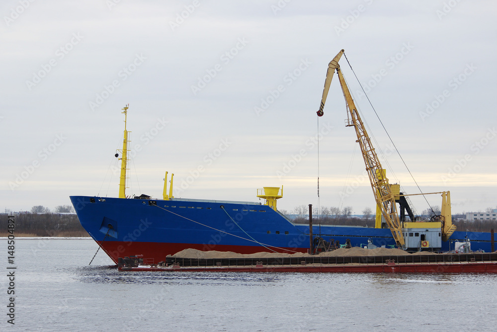 Blue cargo ship and barge with cargo on the river Severnaya Dvina.
