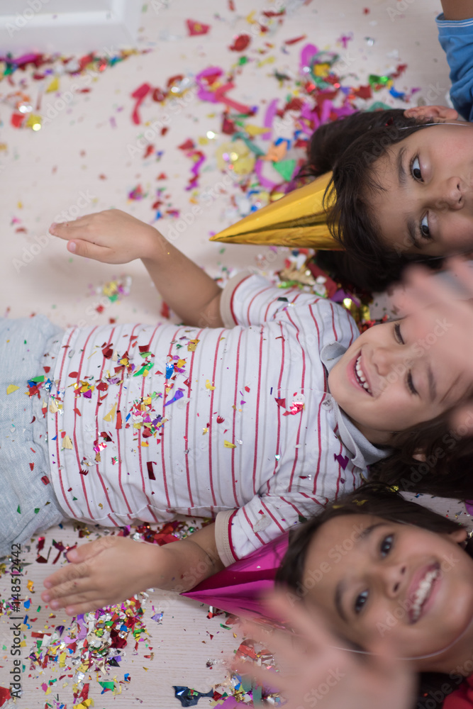 kids blowing confetti while lying on the floor kids blowing confetti while lying on the floor