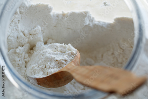 Close-up of a spoon with flour inside a large container