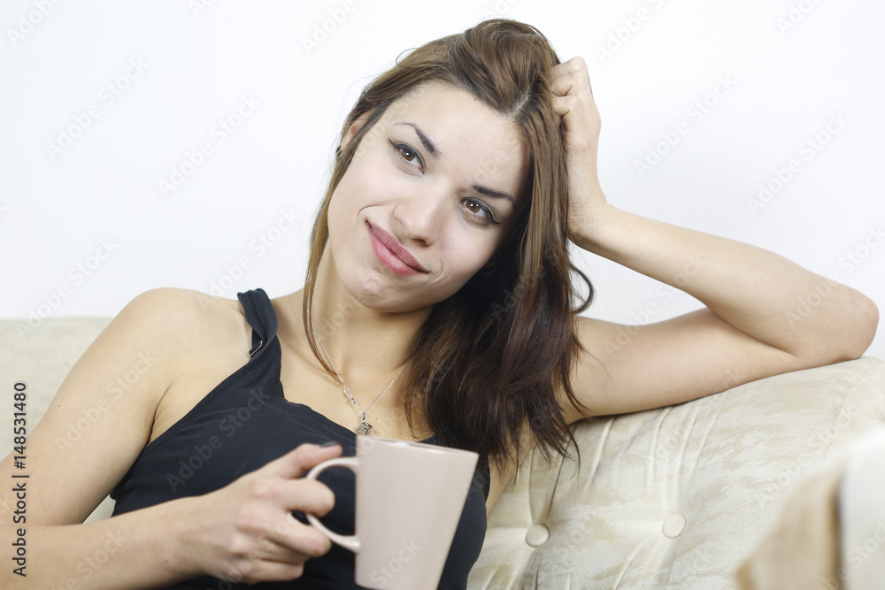 Young attractive woman drinking coffee on sofa and smiling