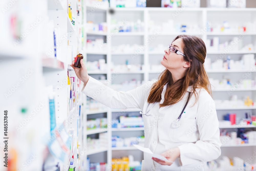 Pharmacist looking and searching for a medication on pharmacy shelf 