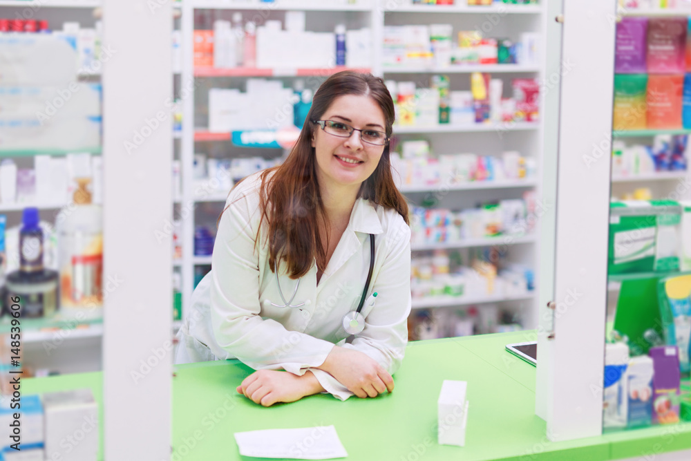 Confident female pharmacist behind the counter smiling 