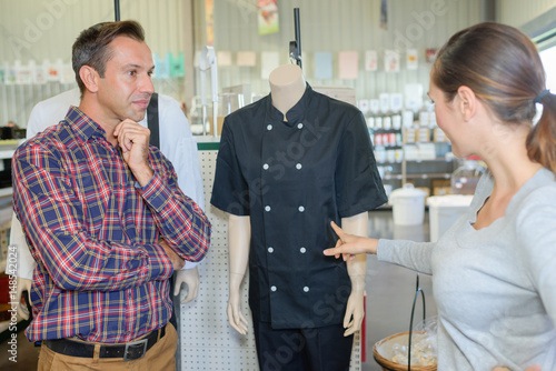 Obraz na plátně woman choosing chefs tunic in commercial wholesale store