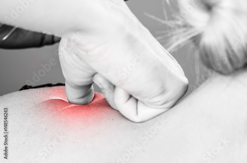 Doctor, physiotherapist examining her patient back and doing decontracting massage in silhouette studio on white background, red pain color. photo