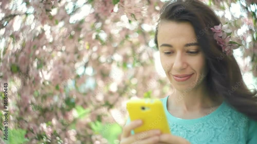 Happy woman with a phone in a blooming spring garden Happy woman with a phone in a blooming spring garden