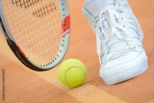 Closeup of tennis racket, ball and shoe