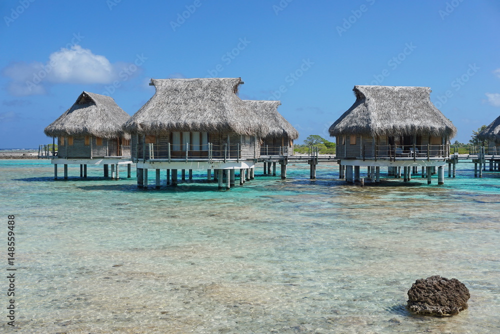 Tropical lagoon and overwater bungalows with thatched roof, atoll of Tikehau, Tuamotu, French Polynesia, south Pacific ocean Tropical lagoon and overwater bungalows with thatched roof, atoll of Tikehau, Tuamotu, French Polynesia, south Pacific ocean