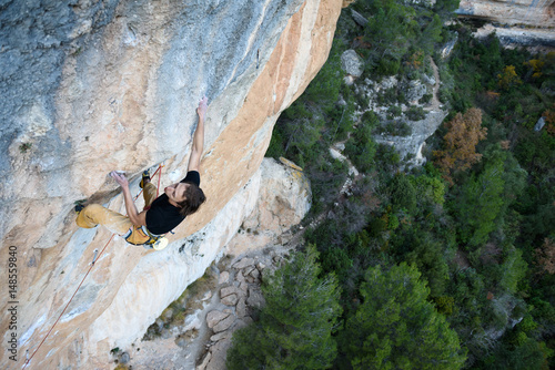 Outdoor sport activity. Rock climber ascending a challenging cliff. Extreme sport climbing. A person achieving his goal. 