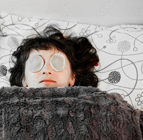 Beautiful young lady posing with cotton pads on her eyes. Moisturizing eye lids, dry eye syndrome.