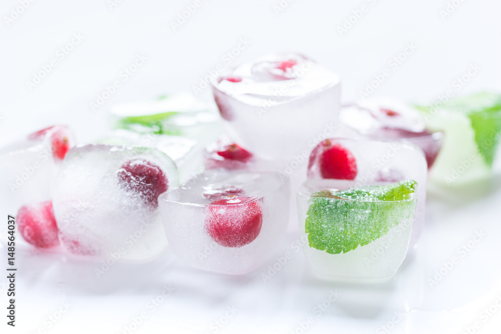 frozen red berries in ice cubes with mint on stone background frozen red berries in ice cubes with mint on stone background