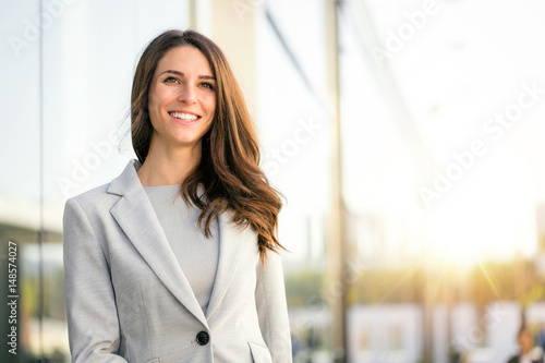 Bright sunny vibrant portrait of beautiful woman business executive style in downtown urban area photo