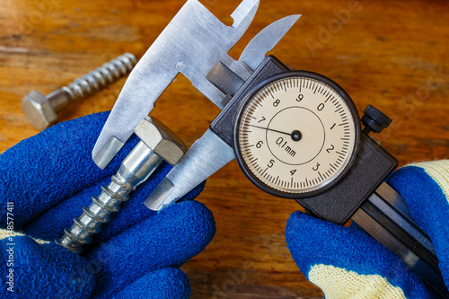 Measurement of the bolt head by a master in gloves with a slide caliper