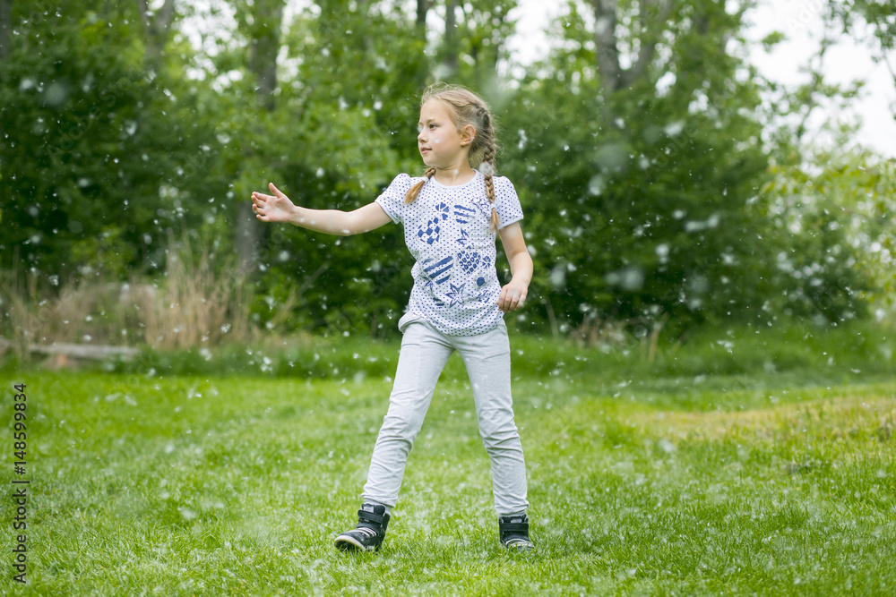 Litlle girl playing with poplar fluff on the green park outdoor. Litlle girl playing with poplar fluff on the green park outdoor.