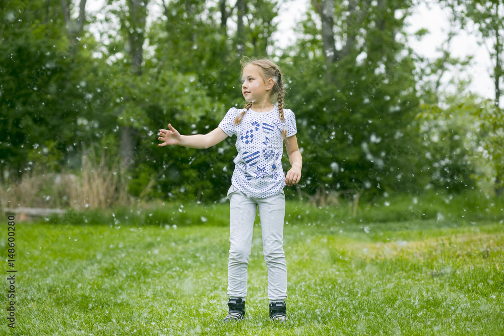 Litlle girl playing with poplar fluff on the green park outdoor. Litlle girl playing with poplar fluff on the green park outdoor.