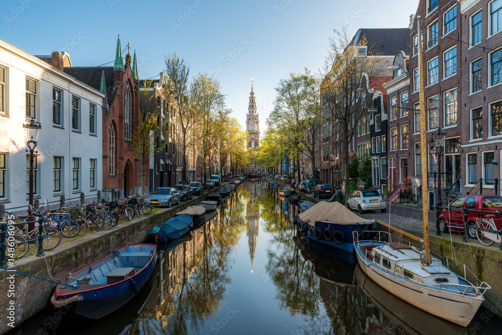 Obraz premium Houses and Boats on Amsterdam Canal, Netherlands. Morning photo of colored houses in the Dutch style with reflection in water in Amsterdam, Netherlands.