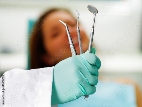 Beautiful woman patient having dental treatment at dentist's office while the doctor is holding his instruments