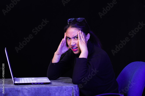 Beautiful girl got stressful in front of her laptop on dark background