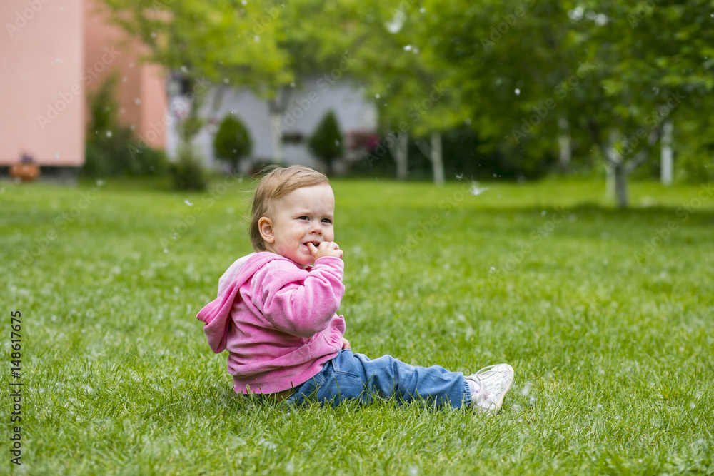 Little baby girl playing with poplar fluff on the green park outdoor. Little baby girl playing with poplar fluff on the green park outdoor.