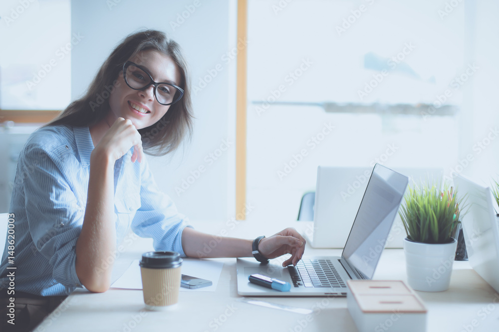 Young woman sitting at office table with laptop Young woman sitting at office table with laptop