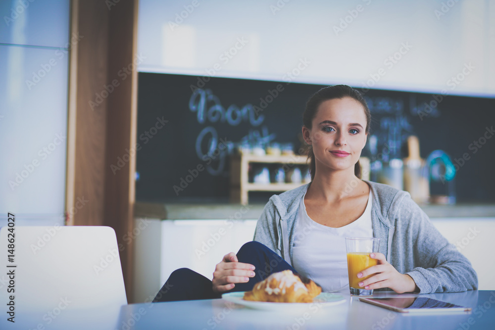 Young woman with orange juice and tablet in kitchen Young woman with orange juice and tablet in kitchen