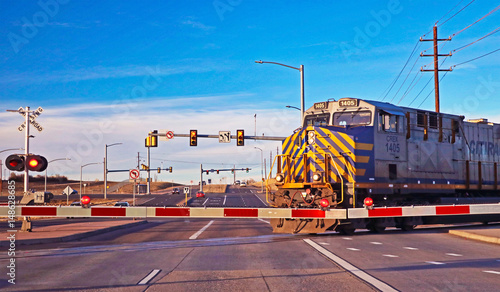 Canvas Print A train crosses a busy street at a railroad crossing