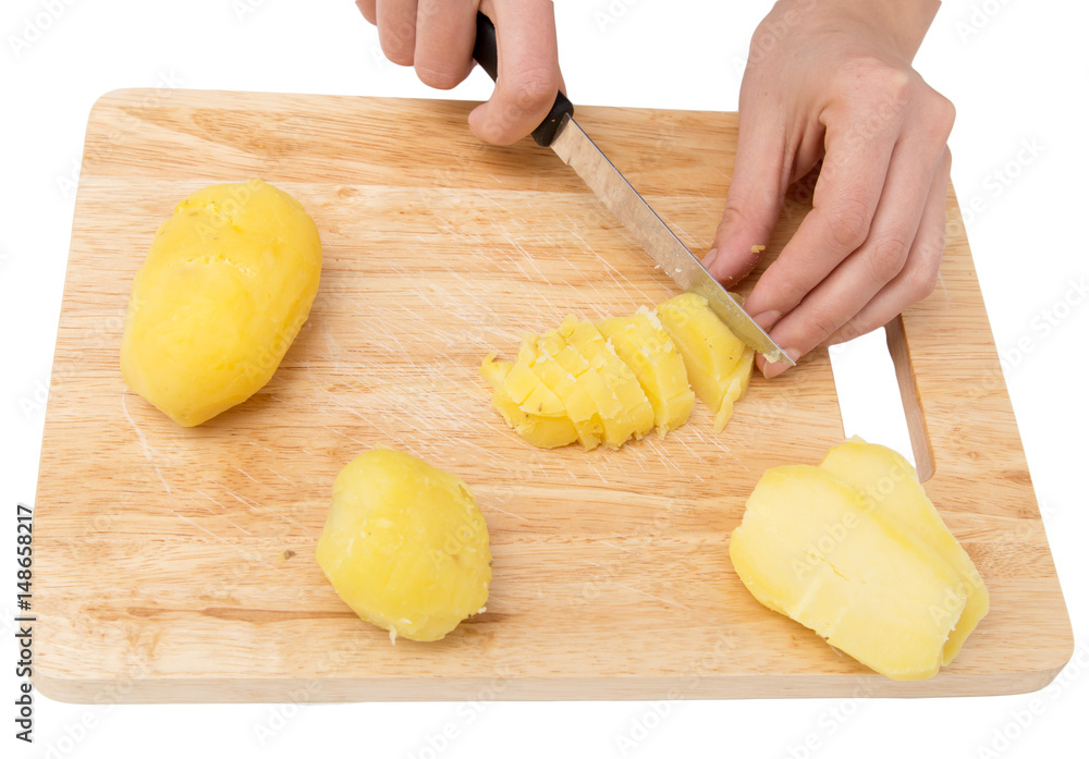 Chef cuts boiled potatoes on board on a white background Chef cuts boiled potatoes on board on a white background