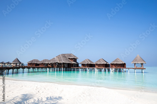 Over Water Bungalows over crystal clear blue ocean sea water with white sand beach