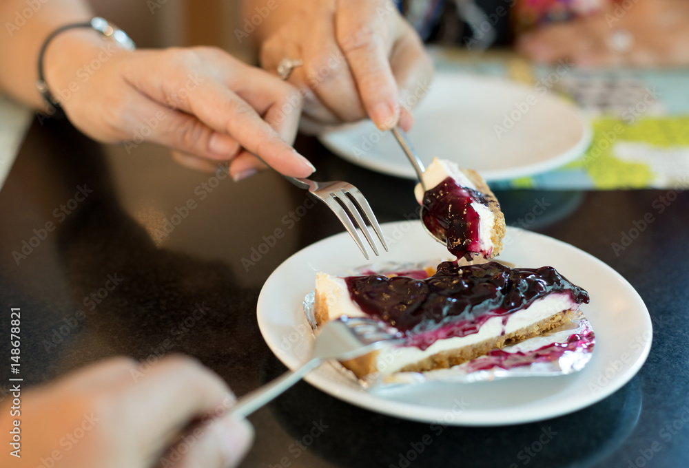 Family time concept hands with fork eating blueberry cheese cake